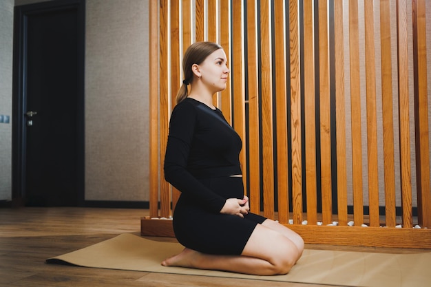 Une jeune femme enceinte fait du sport assise sur un tapis Mode de vie actif d'une femme enceinte Sports pour femmes enceintes