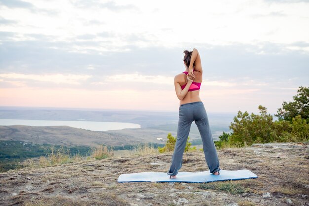 Jeune femme enceinte fait du yoga à l'extérieur