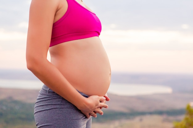 Jeune femme enceinte fait du yoga à l'extérieur