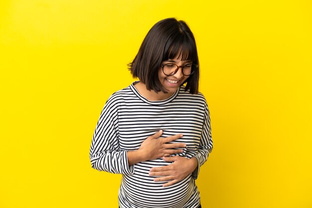 Photo jeune femme enceinte sur fond jaune isolé souriant beaucoup