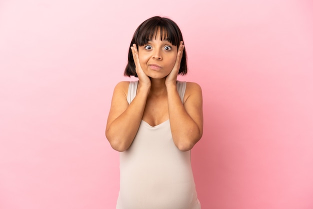 Jeune femme enceinte sur fond rose isolé frustré et couvrant les oreilles