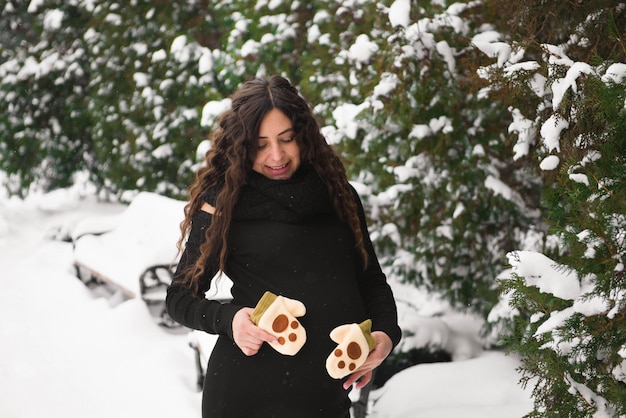 Jeune femme enceinte heureuse dans le parc enneigé