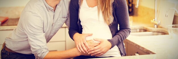 Photo jeune femme enceinte heureuse avec son mari dans la cuisine