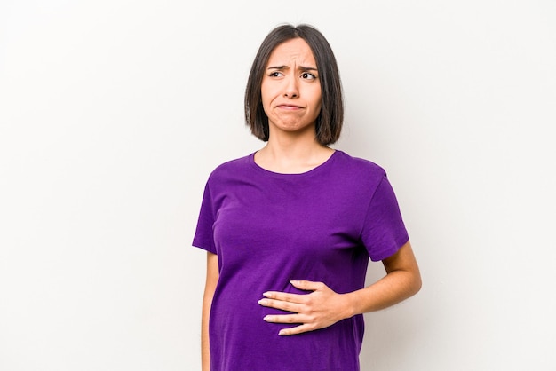 Jeune femme enceinte hispanique isolée sur fond blanc confus se sent douteux et incertain