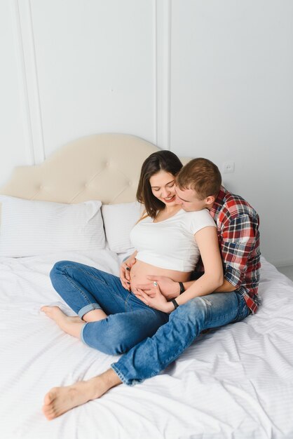 Jeune femme enceinte avec mari sur canapé dans la chambre