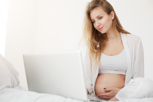 Jeune Femme Enceinte Parcourant Une Boutique En Ligne à La Recherche De Vêtements Pour Tout-petits