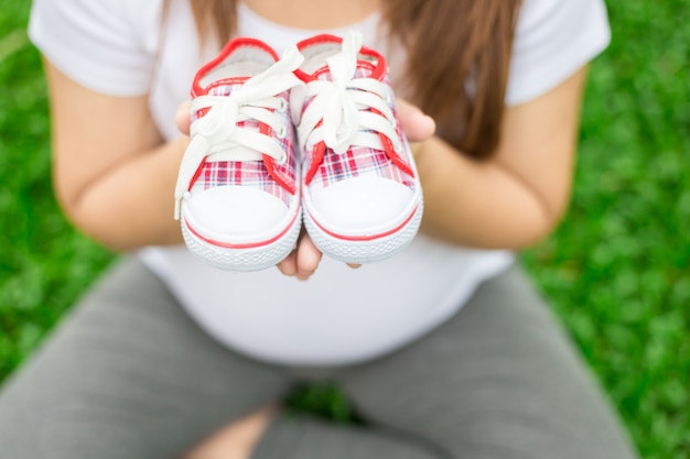 Photo jeune femme enceinte portant des chaussures de bébé sur son ventre