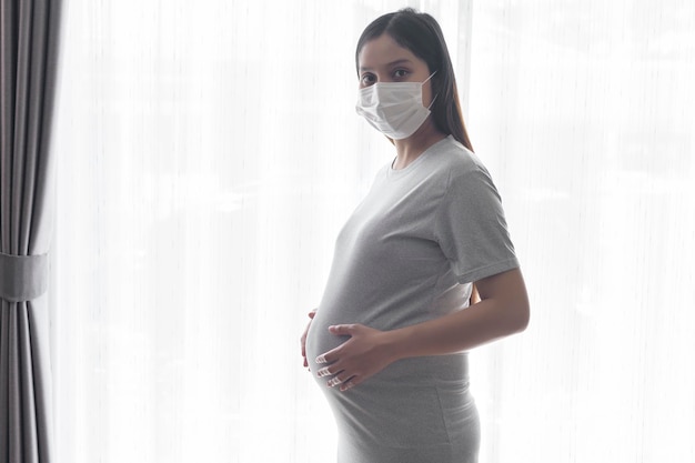 Jeune femme enceinte portant un masque de protection et attendant un bébé en bonne santé et concept de maternité