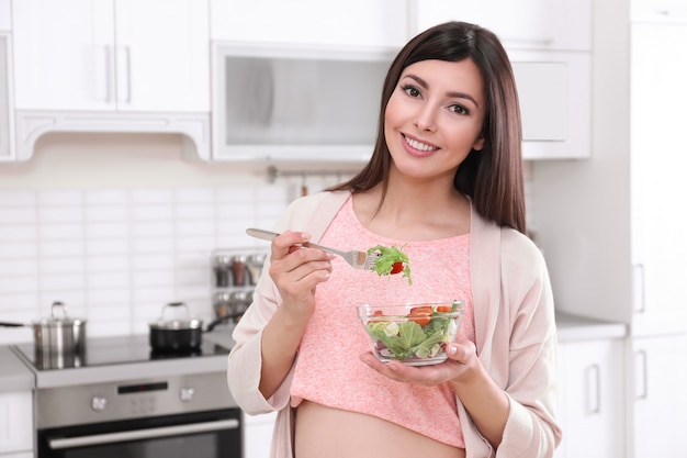 Jeune femme enceinte prenant son petit déjeuner dans la cuisine