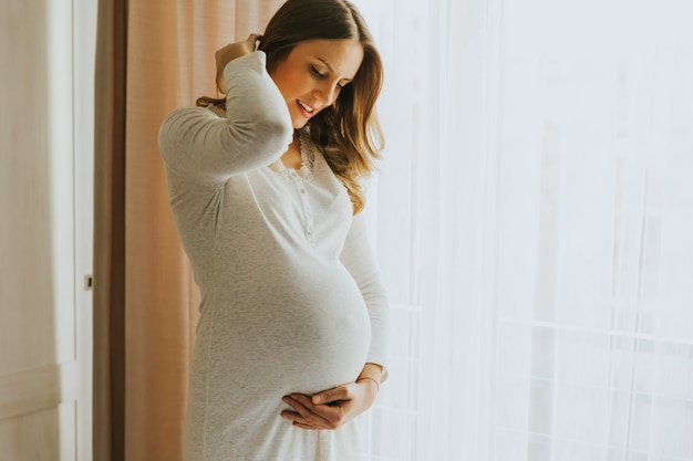 Photo jeune femme enceinte près de la fenêtre