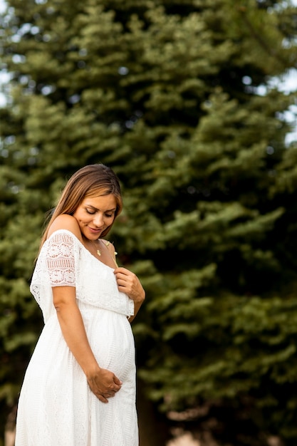 Jeune femme enceinte en robe blanche dans la forêt un jour d'été