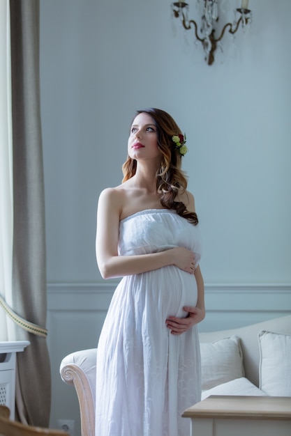 Jeune femme enceinte en robe blanche