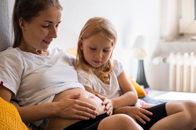 Photo jeune femme enceinte avec sa fille écoutant le rythme du bébé