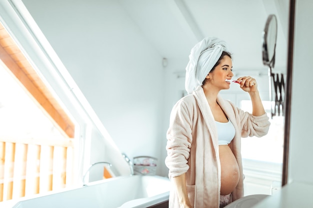 Jeune femme enceinte se brosser les dents dans la salle de bain