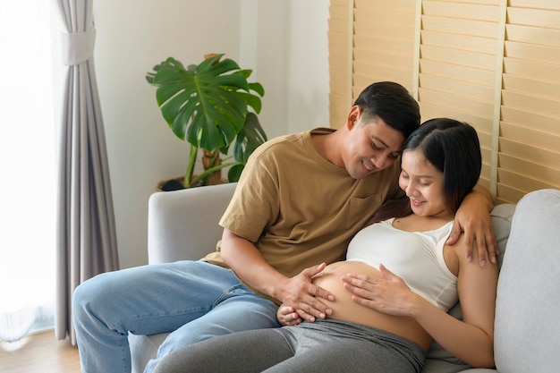 Jeune femme enceinte avec son mari embrassant et attendant un bébé à la maison