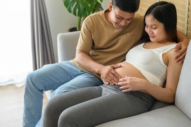 Jeune femme enceinte avec son mari embrassant et attendant un bébé à la maison