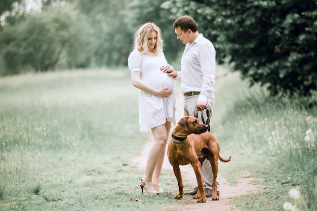 jeune femme enceinte avec son mari lors d'une promenade dans le parc. le concept de bonheur familial