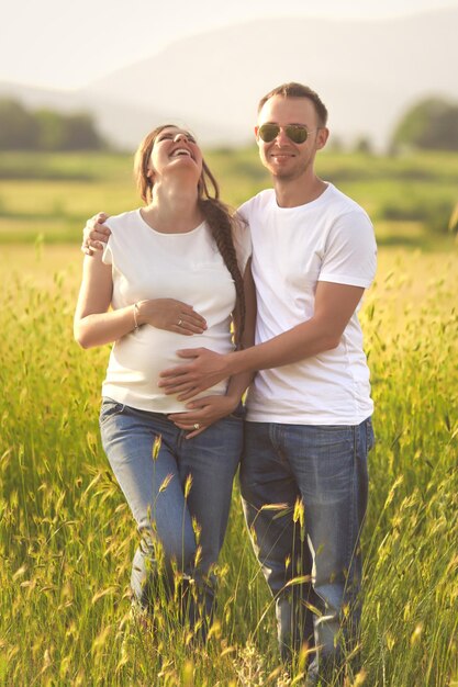 Jeune femme enceinte avec son mari profitant de la nature portant des vêtements décontractés