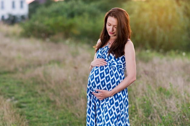Une jeune femme enceinte souriante à l'extérieur