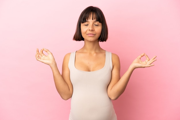 Jeune femme enceinte sur une surface rose isolée dans une pose zen