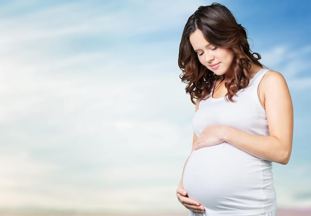 Jeune femme enceinte en t-shirt blanc sur fond