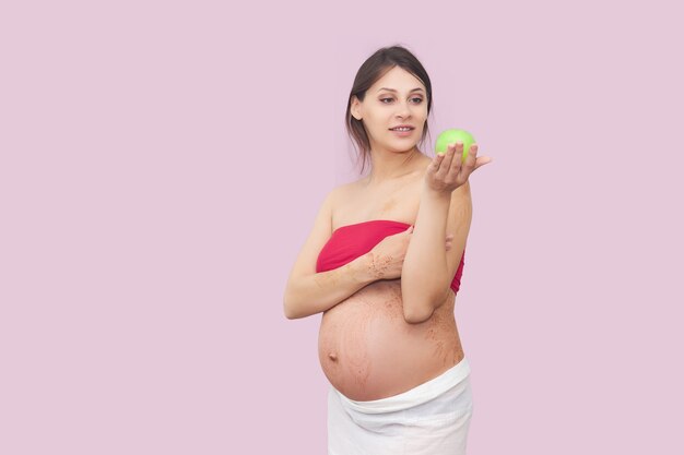 La jeune femme enceinte tient une pomme verte mûre