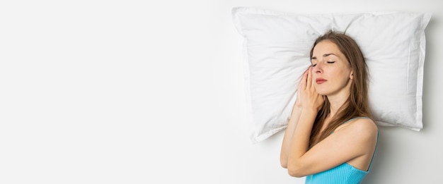 Jeune femme endormie allongée sur un oreiller sur un fond blanc Vue de dessus mise à plat Bannière