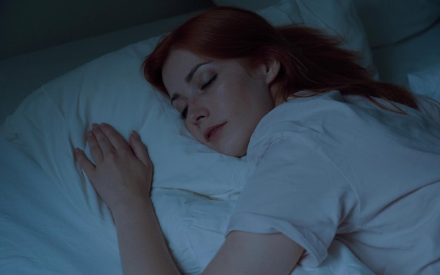 Photo une jeune femme endormie dans son lit la nuit