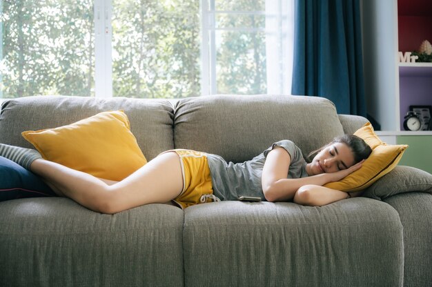 Jeune femme endormie se reposant sur un canapé à la maison, mode de vie confortable pour fille, belle femme heureuse