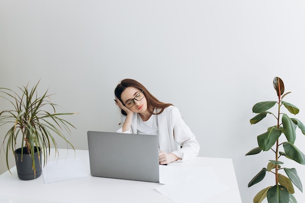 Jeune femme ennuyée vêtue d'une chemise assise sur son lieu de travail