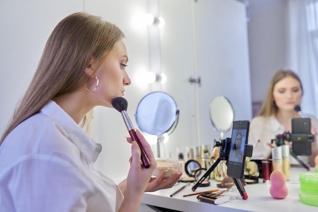 Jeune femme enregistrant un blog de beauté de maquillage vidéo à l'aide d'un smartphone