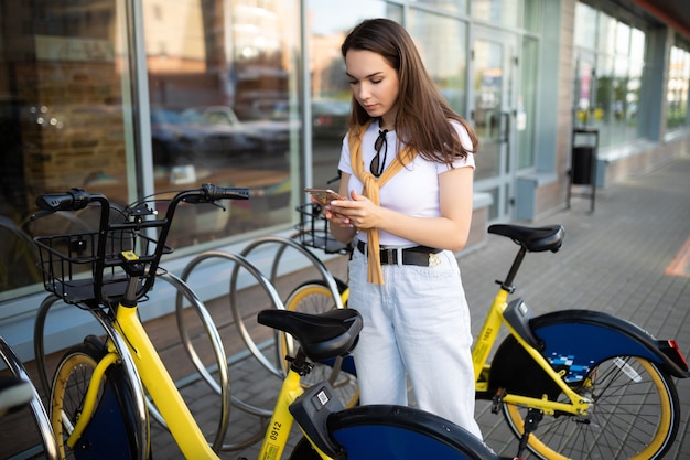 Une jeune femme enregistre une application de location de vélos dans la ville