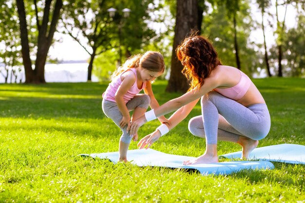 Jeune femme enseignant le yoga à une petite fille dans le parc