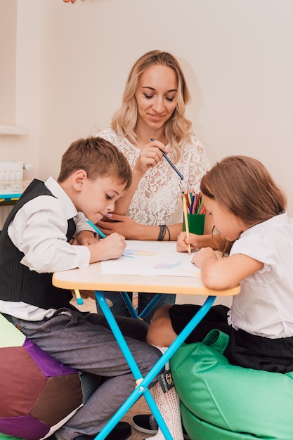 La jeune femme enseigne aux enfants à dessiner