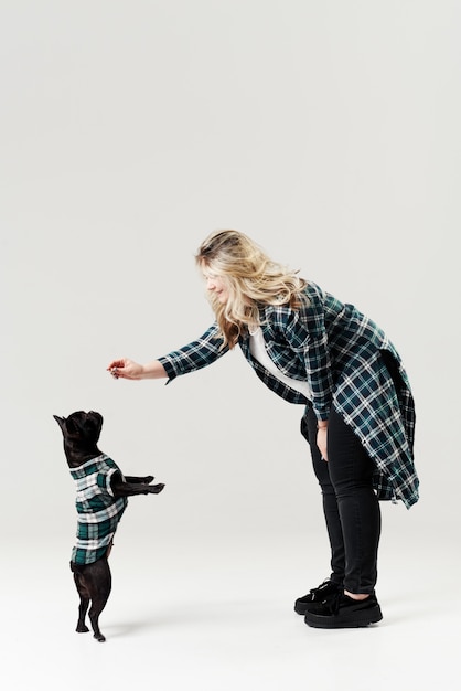 Jeune femme entraîne un chien, un chiot bouledogue français.