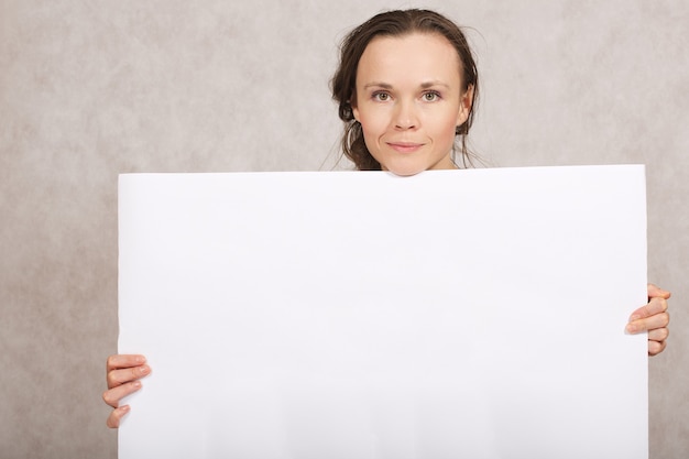 Jeune femme entre 30 et 40 ans garde une feuille de papier blanc