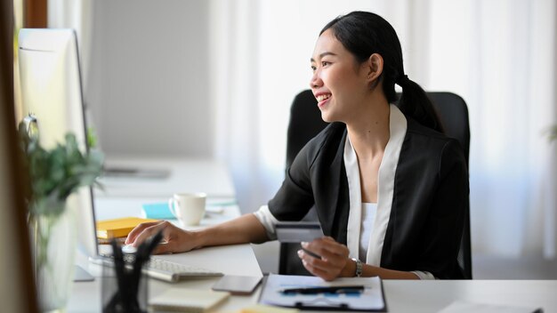 Jeune femme entrepreneure asiatique vérifiant ses stocks sur un ordinateur de bureau, travaillant sur un ordinateur.