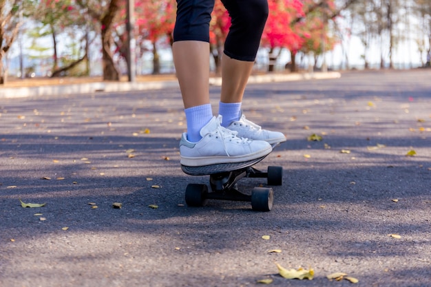 Jeune femme équitation skateboard old-school le long de la rue