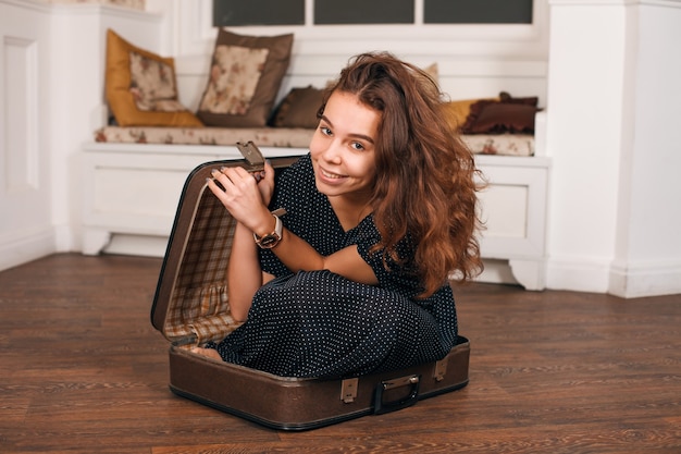 Jeune femme essayant de monter dans une valise.