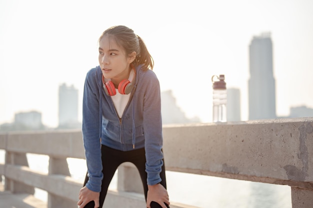 Une jeune femme essuie la sueur après une séance d'entraînement matinale en ville. Une ville qui vit sainement dans la capitale Vue arrière de la ville Exercice, fitness, jogging, course à pied, mode de vie, concept sain.