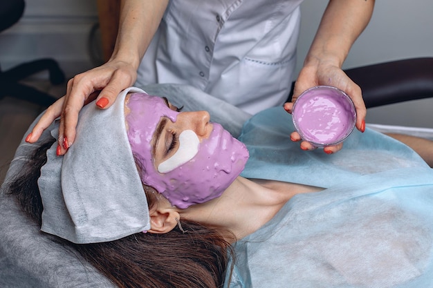 Une jeune femme est allongée sur un canapé dans un salon de beauté avec un masque durcissant sur tout son visage pour avoir une peau douce.