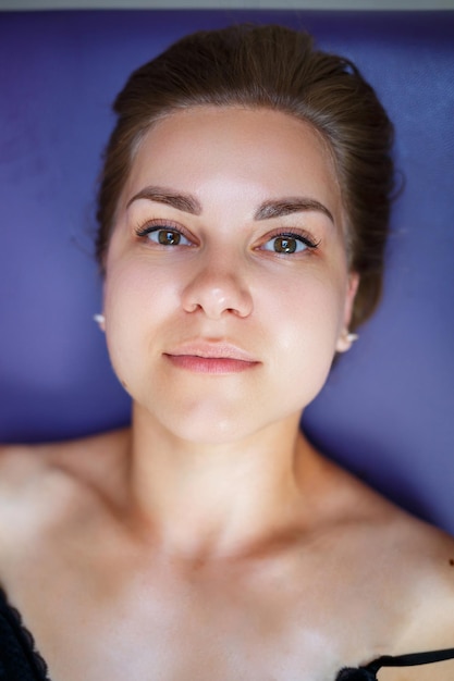 Une jeune femme est allongée sur un canapé et elle se fait masser le visage Soins de la peau Prévention des rides sur le visage Amélioration de la peau Procédures de beauté pour les femmes