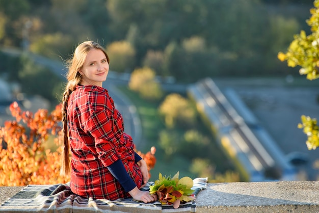 Jeune femme est assise sur une colline surplombant la ville. Vue arrière