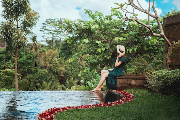 Une jeune femme est assise près de la piscine personnelle ouverte avec vue sur la jungle tropicale, Ubud