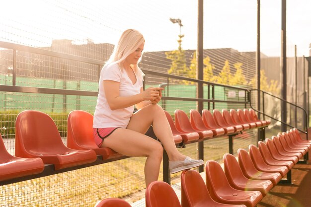 Une jeune femme est assise seule sur les gradins d'un stade