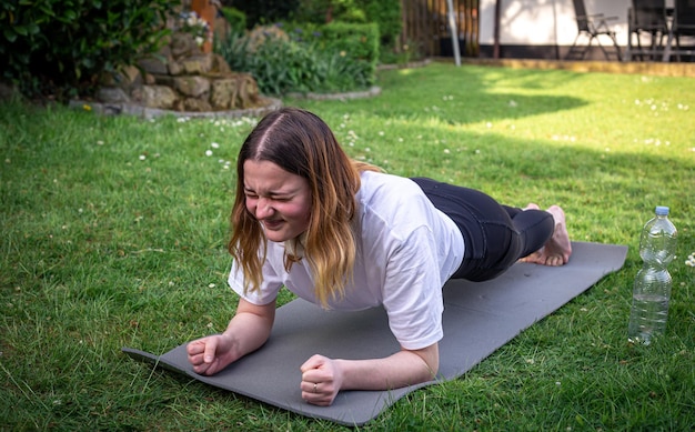 Une jeune femme est engagée dans la forme physique sur un tapis en gros plan de planche nature