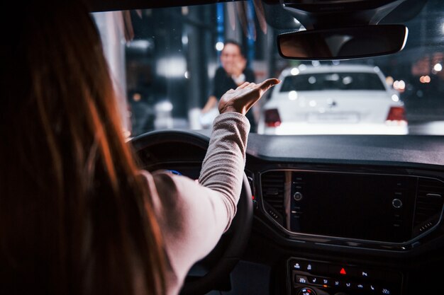 La jeune femme est à l'intérieur d'une toute nouvelle automobile moderne tient la main devant elle à la fille.