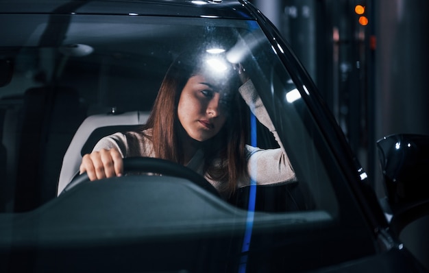 La jeune femme est à l'intérieur d'une toute nouvelle automobile moderne.