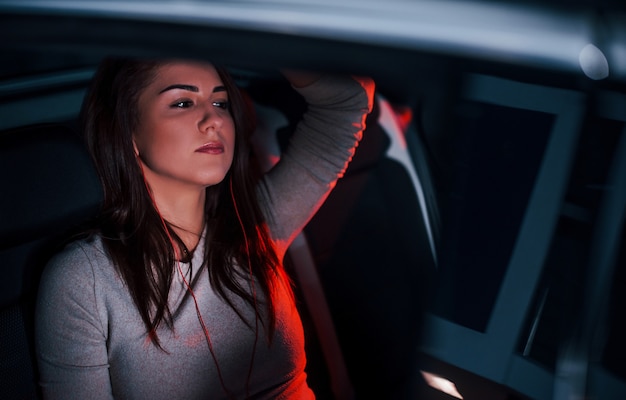 La jeune femme est à l'intérieur d'une toute nouvelle automobile moderne.