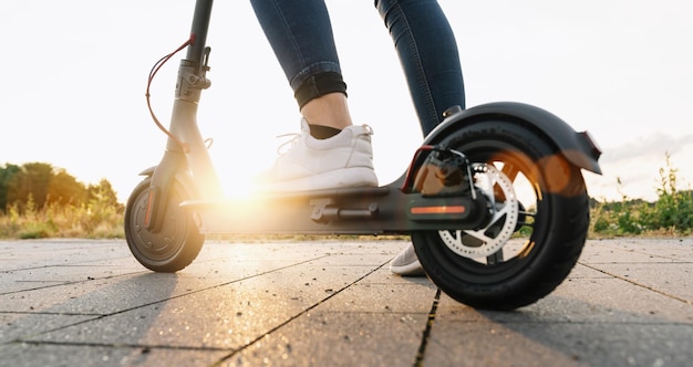 Photo jeune femme est prête à découvrir la ville urbaine au coucher du soleil avec un scooter électrique ou un escooter image de concept de transport urbain électrique